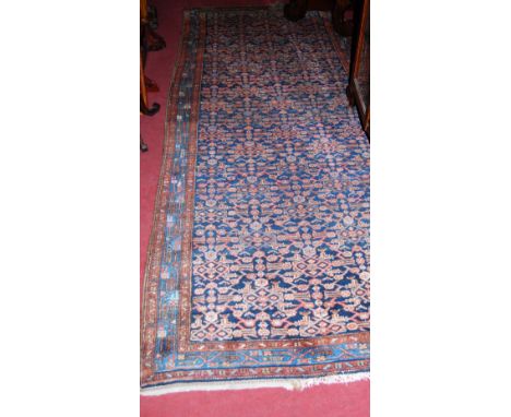 A Persian woollen blue ground hall runner, having a heavy floral central ground within trailing tramline borders, 305 x 121cm