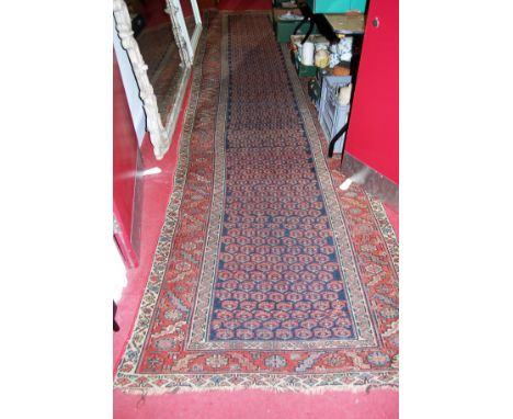A Persian woollen blue ground hall runner, having continuous central ground within trailing tramline borders, 446 x 116cm