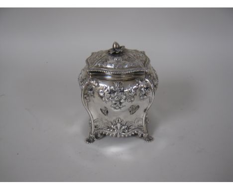 A George III silver Tea Caddy and Cover of bombe form with floral and scroll embossing, gadroon rims on shaped feet, London 1