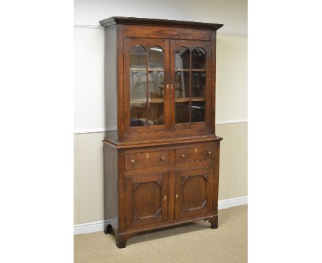 An early 19th Century oak Bookcase with pair of glazed doors above two short drawers with mahogany inlay and pair of panelled