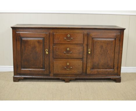An 18th Century oak Dresser Base fitted three central drawers flanked by pair of fielded panelled doors on bracket feet, 5ft 