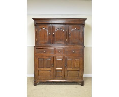 An 18th Century oak Court Cupboard with three cupid's bow panelled doors fronted by turned finals, the base fitted three shor