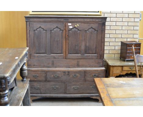 An 18th Century squat Linen Press fitted with a pair of cupid's bow panelled doors above base fitted five drawers and mounted