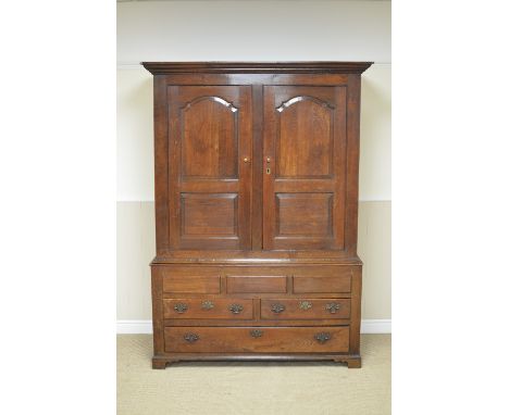 An 18th Century oak Hall Cupboard with pair of arched fielded panel doors enclosing hanging space, two short and one long dra