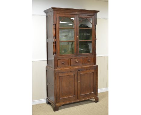 A 19th Century oak Cupboard, the upper section with pair of glazed doors and three short drawers flanked by turned and square
