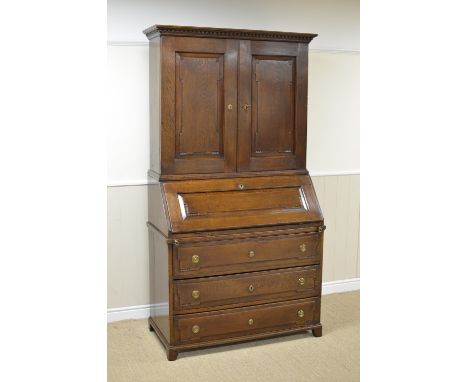 An antique oak Bureau Cabinet with pair of solid panelled doors enclosing shelves, six small drawers flanked panelled door, t