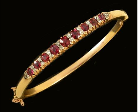 A Ruby and Diamond hinged Bangle, the front pavé-set graduated cushion-cut rubies interspersed with pairs of old-cut diamonds