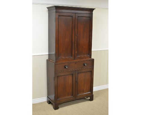 A Georgian oak Cabinet with pair of solid panelled doors enclosing shelves, the base fitted one long drawer above pair of sol