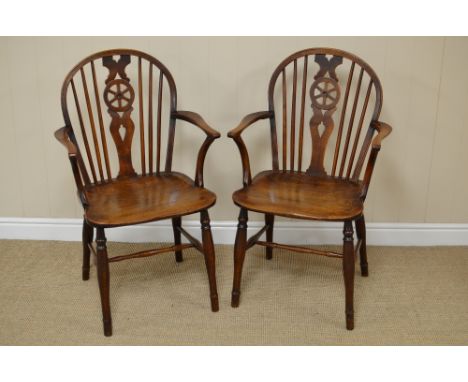 A pair of early 19th Century elm and fruitwood Windsor Elbow Chairs with wheel and stick back, shaped arms, solid seat on tur