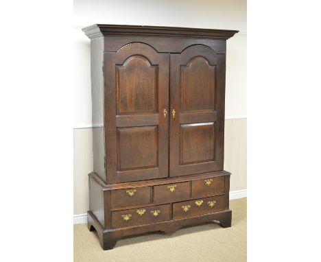 An 18th Century oak Hall Cupboard with pair of arched fielded panel doors enclosing hanging space, five short drawers beneath