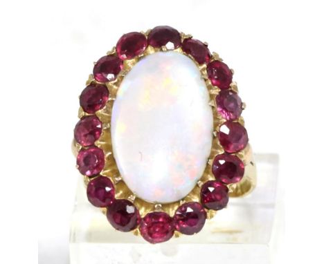 An opal and ruby cluster ring, an oval cabochon opal within a border of round cut rubies, to forked shoulders, finger size M 