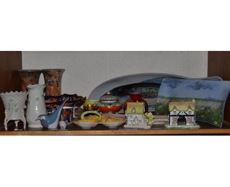 A shelf of ceramics including; Highland stoneware dishes, Coalport cottages, Belleek vases, Mailing, Beswick, Poole, Carlton 