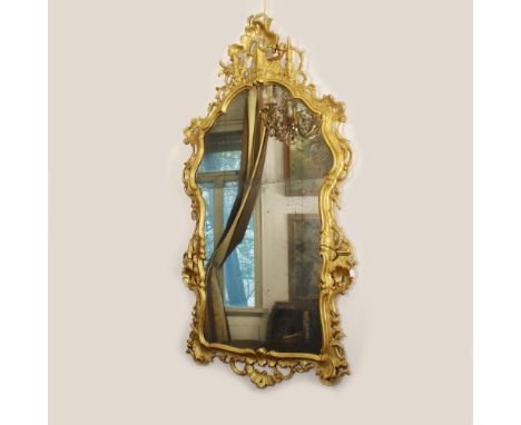 Gilded wood mirror Italy, 20th centuryshaped frame carved with vegetal volutes and architectural elements158x85 cm.