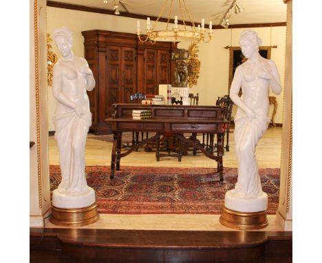 Pair of white glazed ceramic sculptures Italy, 20th centurydepicting two female figures resting on golden circular bases170x5