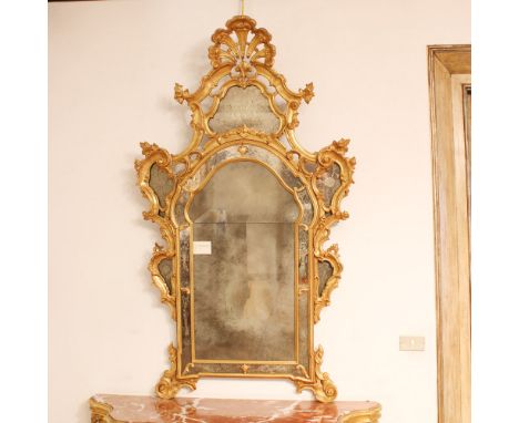 Gilded wood mirror Italy, 20th centuryshaped frame carved with plant motifs and opposite volutes, side mirrors acid-etched wi