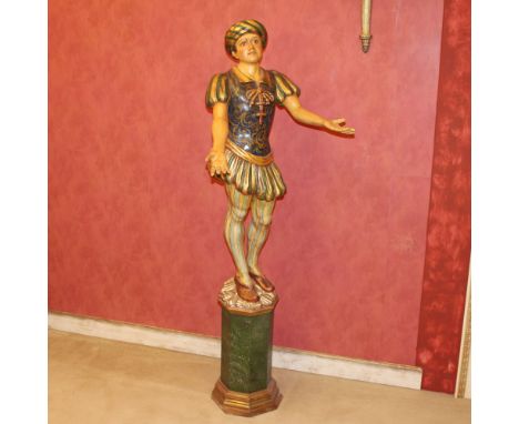 A lacquered and gilded wood sculpture Italy, 20th centurydepicting a character in historical costume resting on an octagonal 
