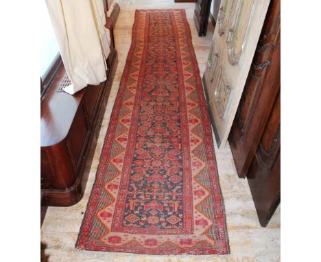 Carpet runner 20th centurydecorated with floral, plant and geometric patterns on a red and blue background, wears and defects
