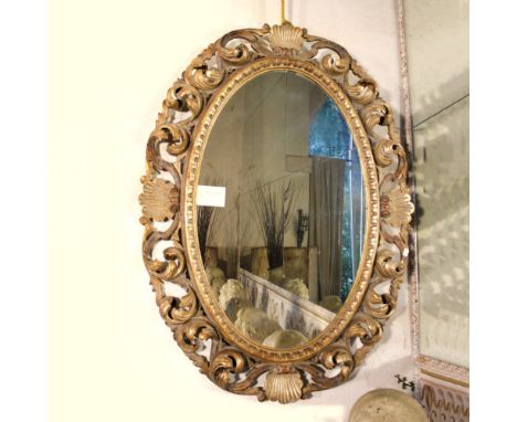 Oval gilded wood mirror Italy, 20th centuryframe carved with plant scrolls and shells motifs122x88 cm.