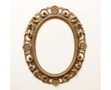 Lacquered wood mirror Italy, 20th centuryoval frame openworked and carved with shells and volutes motifs, defects132x105 cm.