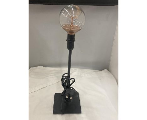 A BLACK TABLE LAMP WITH A THIN STEM AND AN EDISON TYPE BULB 