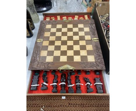 A CHESS SET WITH A WOOD AND RESIN TOP AND WOODEN CHESS PIECES CONTAINED IN DRAWERS, WITH BRASS HINGES AND CARRYING HANDLES 