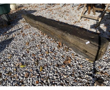 A LARGE VINTAGE OAK POST WITH ONE POINTED END AND A HOLE THROUGH THE MIDDLE, BELIEVED TO BE FROM AN OLD WATER PUMP 