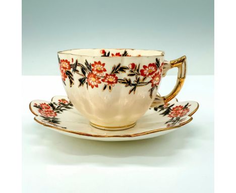 A cream-colored teacup and saucer set that are decorated with a daisy wreath for their design along with gold trim at the bor