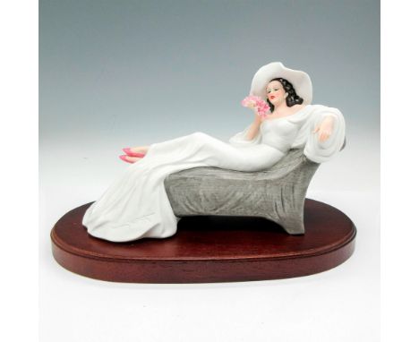 Matte finished figurine lounging in a long white dress holding pink flowers. Signed by artist. Limited edition 973 of 7500. E