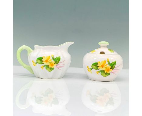 A sugar bowl and creamer that are painted white and decorated with yellow flowers along with borders painted pastel green. Sh