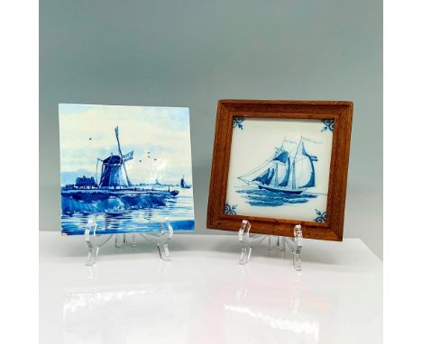 A pair of two blue art tiles, one depicting a scene of a windmill on a countryside harbor and the other is a framed tile with