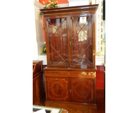 An Edwardian inlaid mahogany library bookcase with egg and dart and ovolo frieze, shelved and glazed top section, the base wi