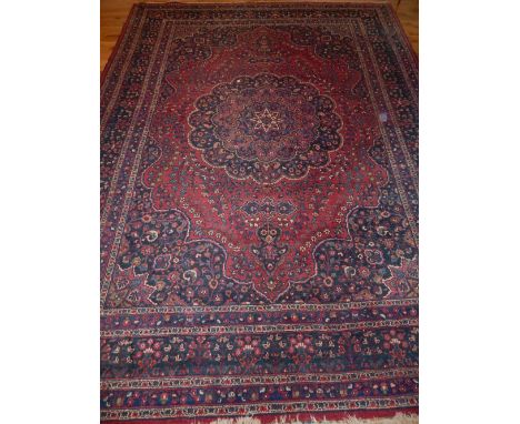 Large North West Persian carpet, traditional floral design with lobed central medallion over red and indigo ground, fringed, 