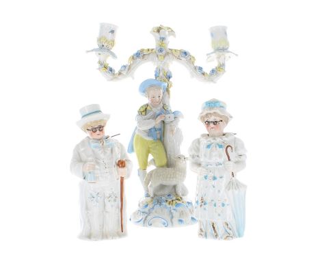 Late 19th century German porcelain figural two branch candelabra, modelled with a shepherd boy with a dove and sheep upon a n