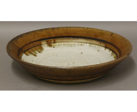 *A stoneware dish,by Richard Batterham (b.1936), with a brown-glazed rim and a light celadon centre, 31.5cm diameter*Artist's
