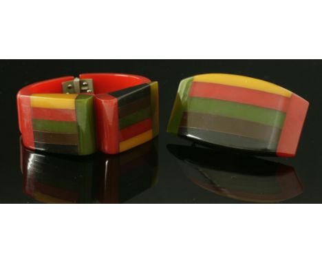 An Art Deco Bakelite hinged bangle and brooch suite,the bangle with a hinged red tapering body, with laminated fold-over styl