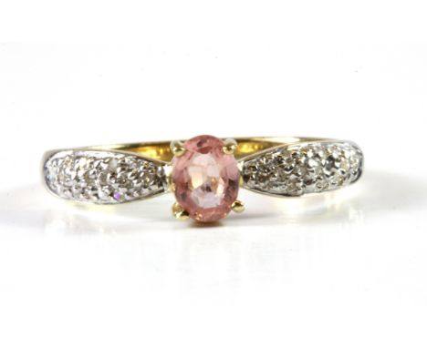 A 9ct yellow gold ring set with an oval cut light pink sapphire and diamond set shoulders, (L.5).