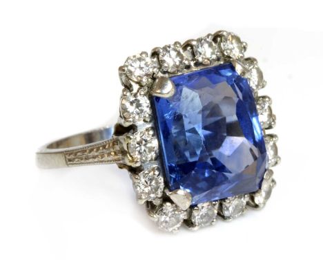 An American sapphire and diamond cushion-shaped cluster ring, with a modified cushion cut sapphire, four claw set at the cut 