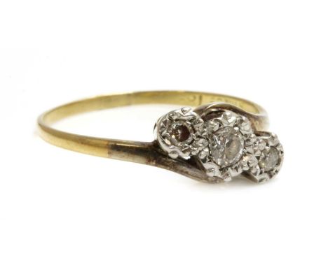 A three stone diamond crossover ring, with three graduated brilliant cut diamonds, illusion set to white collets, with yellow