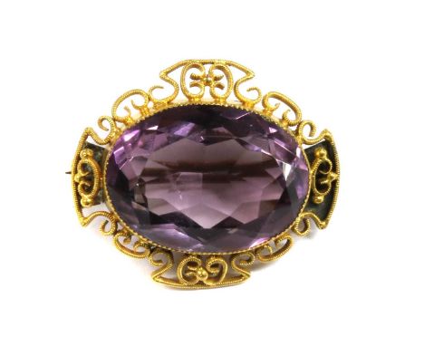 A Victorian gold amethyst brooch, an oval mixed cut amethyst, milligrain set to a plain collet, with scrolling milled wire fr