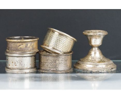 Four assorted silver hallmarked napkin rings together with a silver hallmarked candlestick. Napkin rings to include engine tu