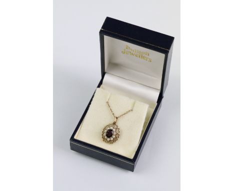9ct gold garnet and pearl pendant necklace. The necklace having a fine link chain with pierced gold pendant set with an oval 