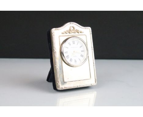 Kitney &amp; Co silver fronted easel back clock timepiece having a round face with roman numerals to the chapter ring with ga