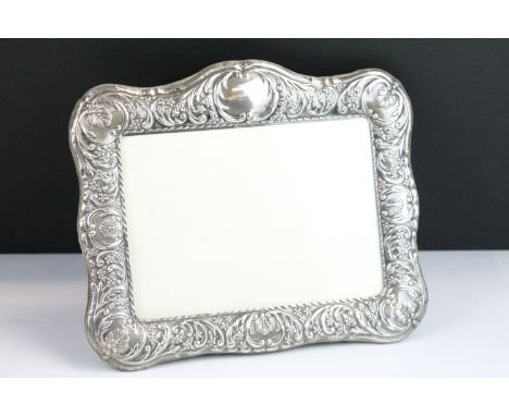 Silver fronted photo frame with moulded scrolled details and easel back. Hallmarked Sheffield 1995. Measures 25cm wide. 