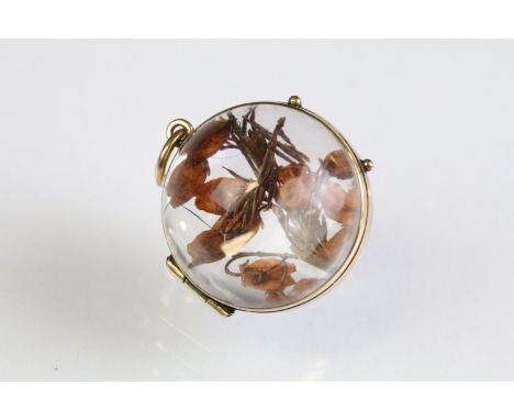 19th Century Victorian pool of light rock crystal locket of orb shape with 9ct gold banding, housing a pressed flower within.