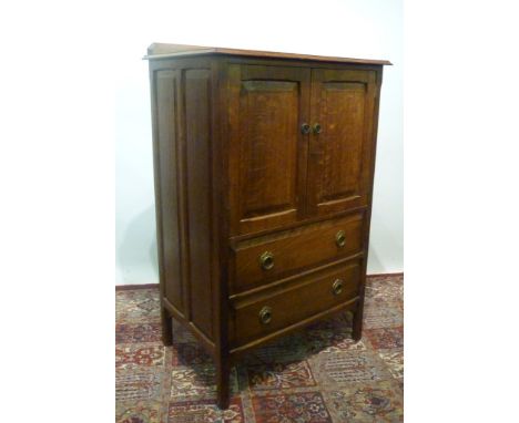 An Oak Side Cabinet, with two panelled doors enclosing shelf above two drawers raised upon square legs