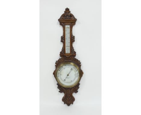 An aneroid barometer and thermometer, in a carved oak case