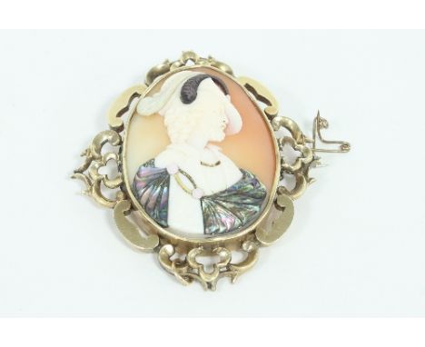 An oval shell cameo brooch with applied mother of pearl details, depicting a gentleman in a plumed hat and cloak, set in a pi