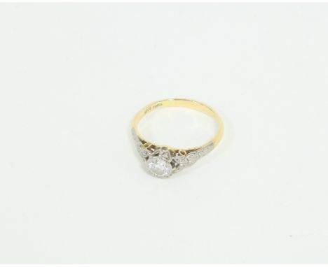 A diamond solitaire ring, the claw set stone to leaf decorated shoulders, on an 18ct gold shank, ring size O Condition Report