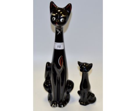 A 1970's stylised black  cat, with elongated neck, silvered eyes and bow, picked out in red, 35cm high;  another, smaller, 15