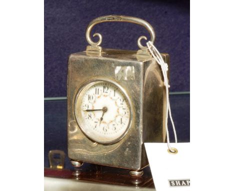 An Edwardian silver cased travel/desk clock, hallmarks for London, of square form with carry handle above a white foliate ena